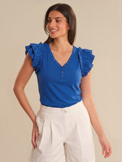 Woman wearing a blue top with ruffled sleeves on a beige background