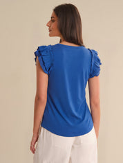 Woman wearing a blue top with ruffled sleeves on a beige background