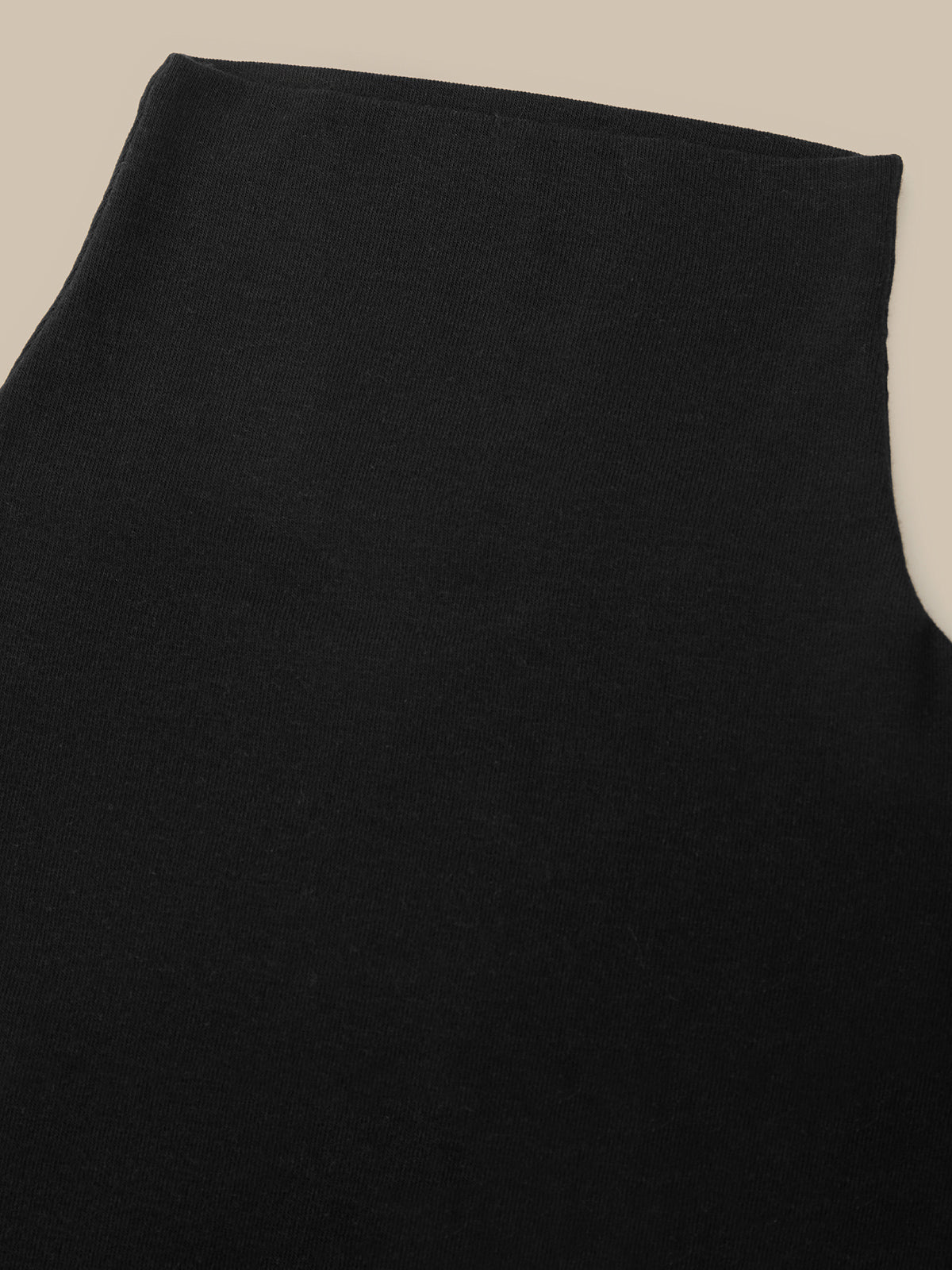 A close-up of a black sleeveless top or dress, showing the smooth fabric texture and a wide neckline, set against a plain beige background.