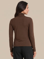 A woman shown from the back wearing a fitted brown long-sleeve turtleneck top and black pants against a plain beige studio background.