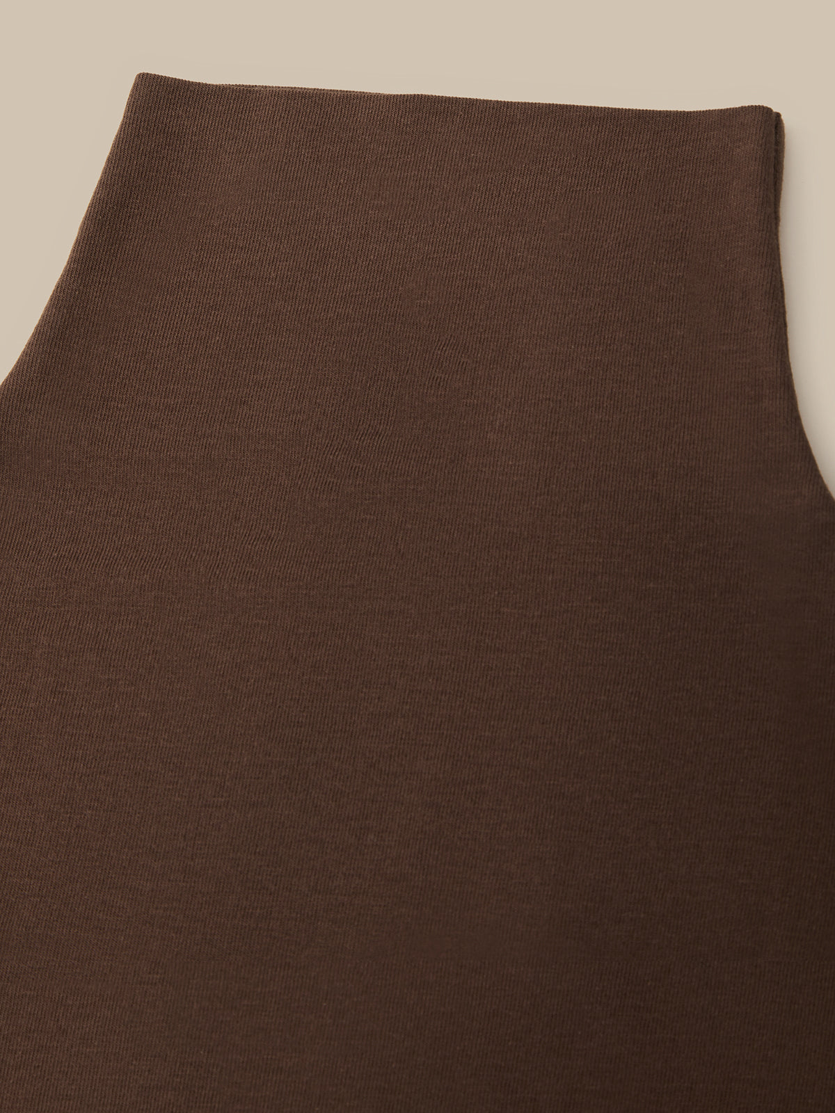 Close-up of a dark brown knit fabric, showing the texture and color of the material against a neutral beige background.