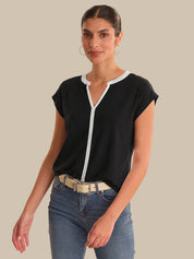 Woman wearing a black top with a white zipper and blue jeans on a beige background