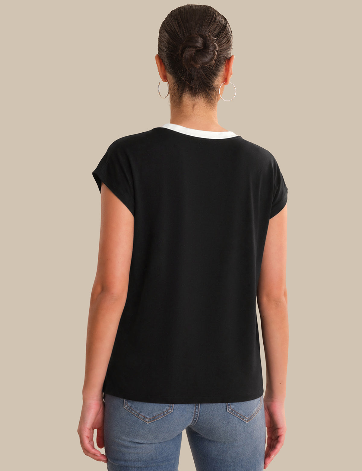 Person wearing a black t-shirt and blue jeans on a beige background