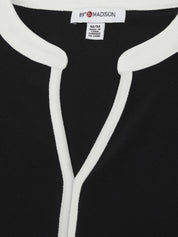 Close-up of a black garment with white piping and a visible label.