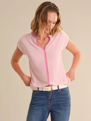 Woman wearing a pink tipped top with blue jeans on a beige background