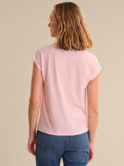Woman wearing a pink t-shirt and blue jeans on a beige background
