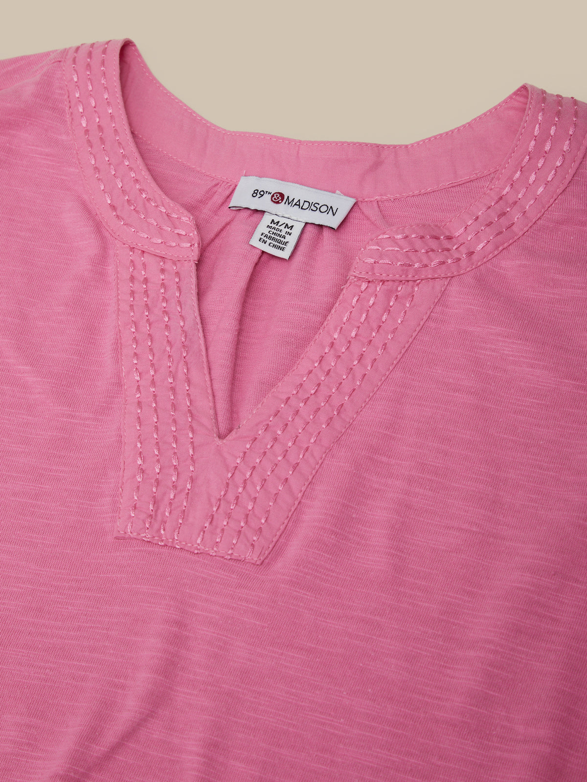 Close-up of a pink shirt with a brand label on a beige background