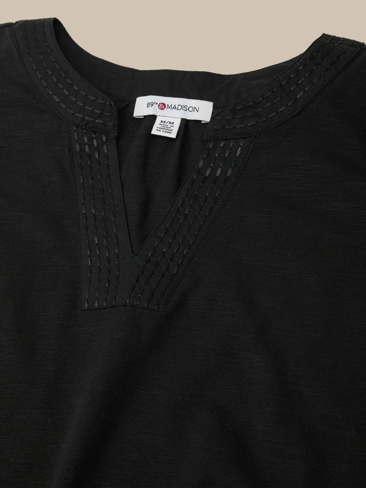 Black garment with brand label on a beige background