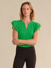 Woman wearing a green top with ruffled sleeves against a beige background