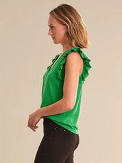Woman wearing a green sleeveless top with ruffled shoulders on a beige background