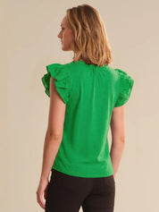 Woman wearing a green top with ruffled sleeves on a beige background
