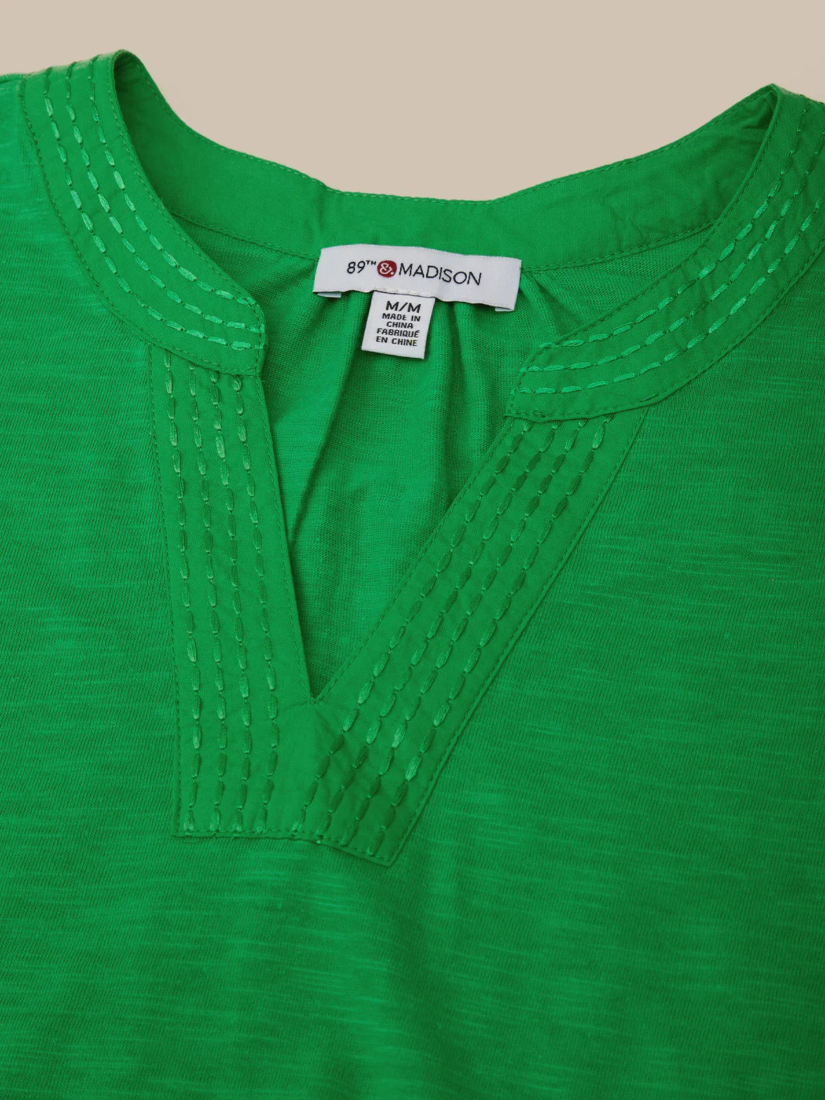 Green shirt with a brand tag on a beige background