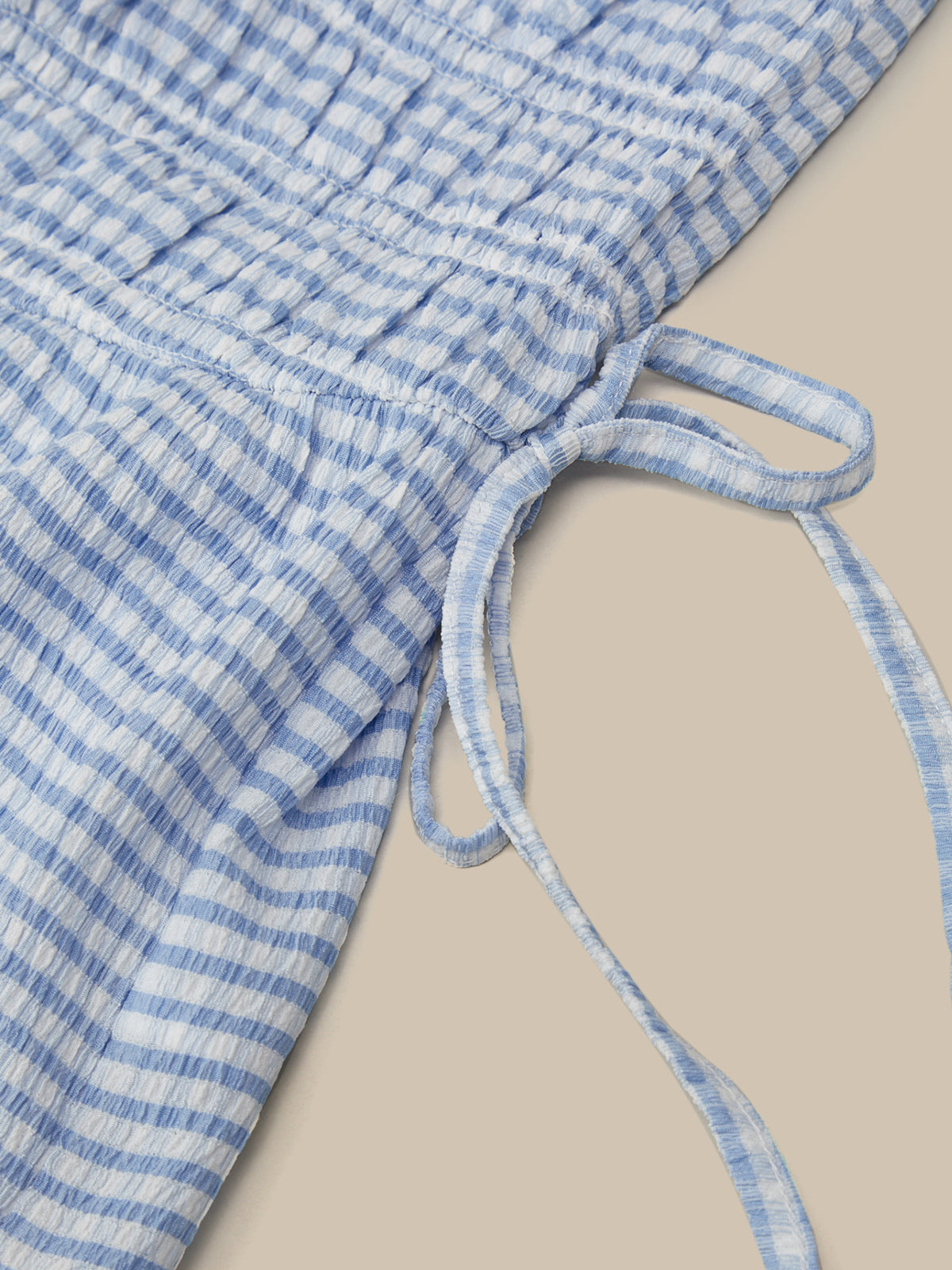 Blue and white checkered fabric with a tie on a beige background