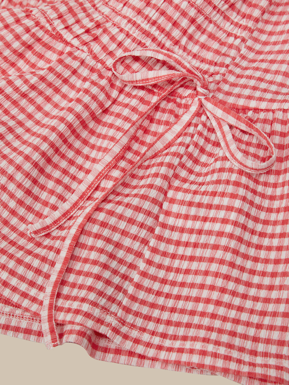 Red and white checkered fabric with a tie detail on a beige background