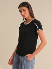 Woman wearing a black t-shirt with white trim on a beige background