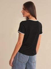 Woman wearing a black t-shirt with white trim on a beige background