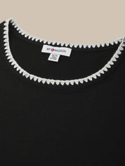 Black garment with white trim and a brand label on a beige background
