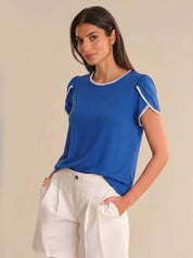 Woman wearing a blue top with white trim against a beige background