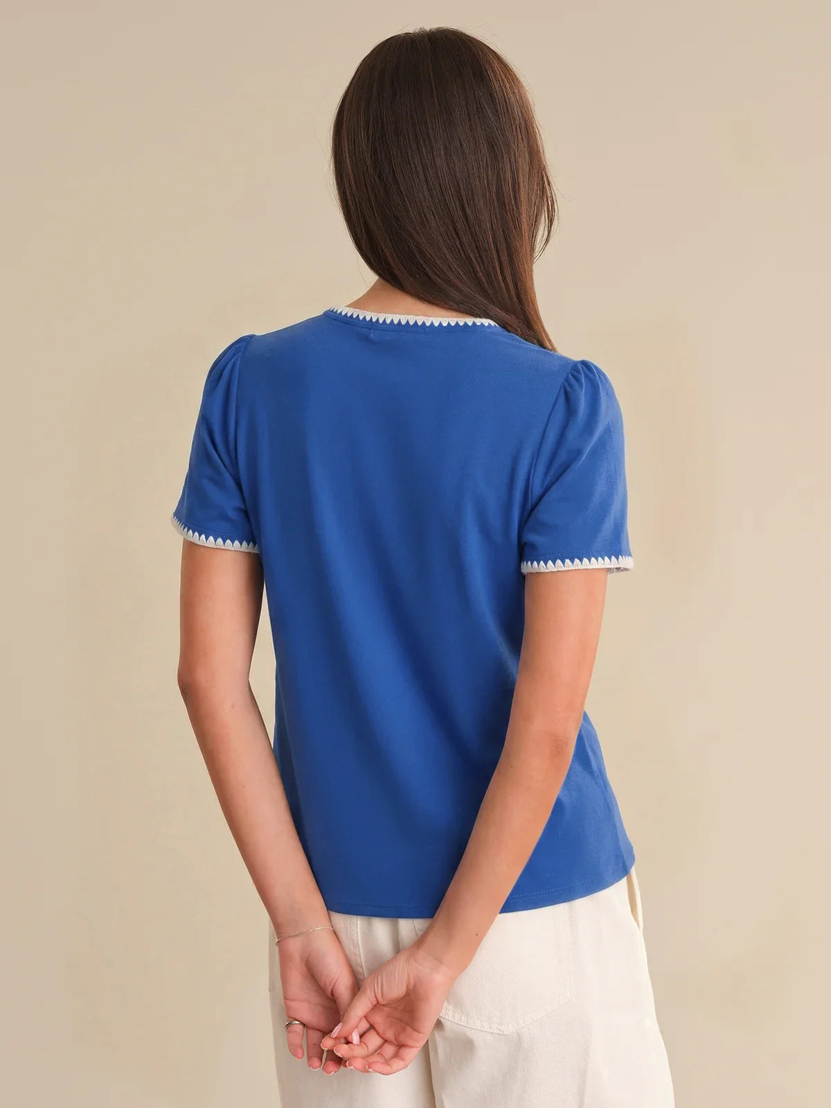 Person wearing a blue shirt with white trim on a beige background