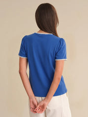 Person wearing a blue shirt with white trim on a beige background