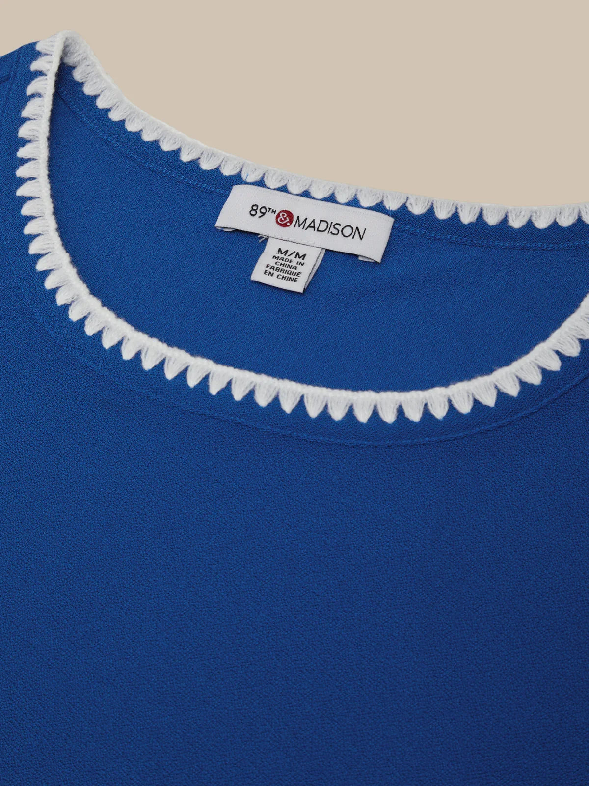 Blue shirt with white trim and a visible label on a beige background