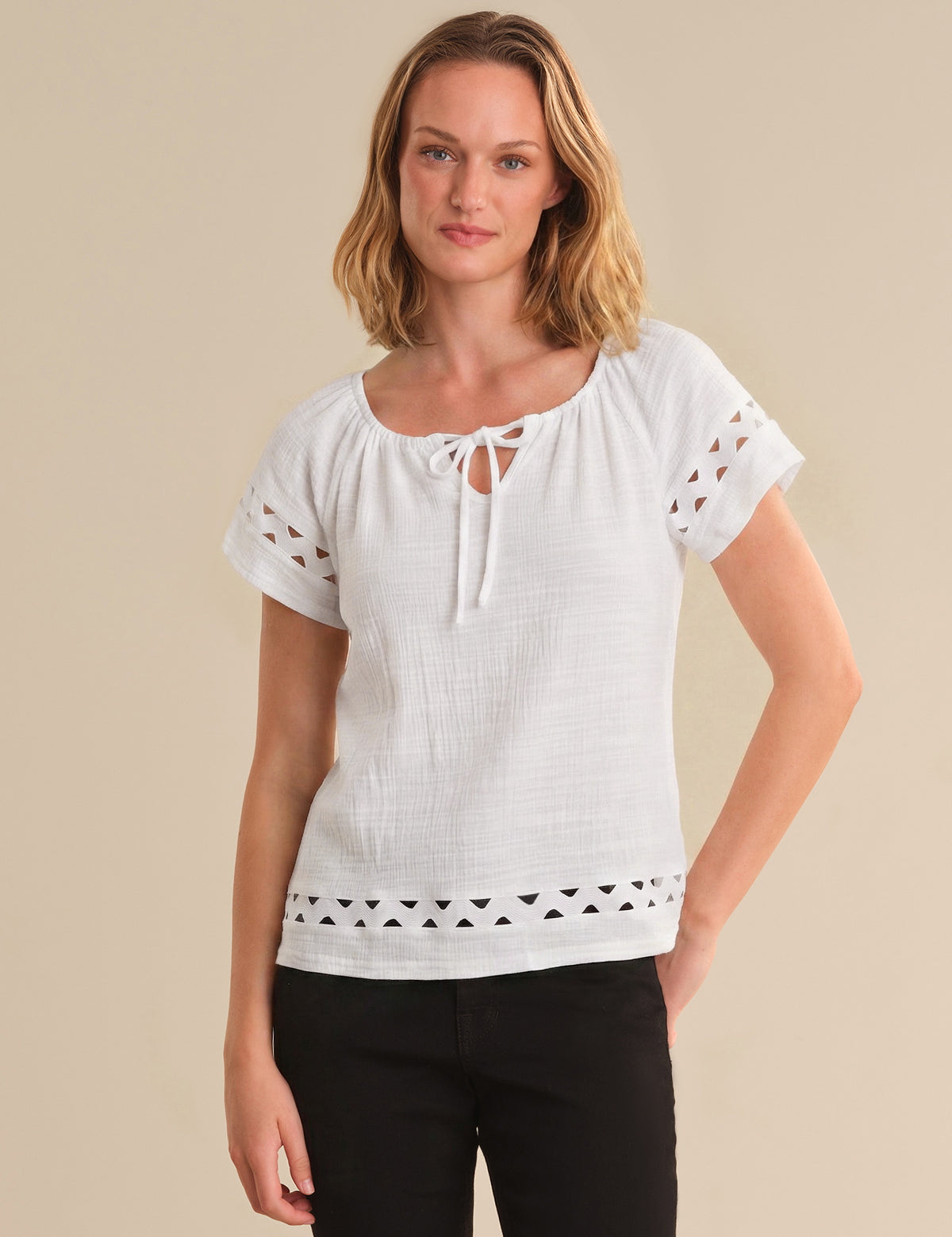 Woman wearing a white blouse with lace details on a beige background