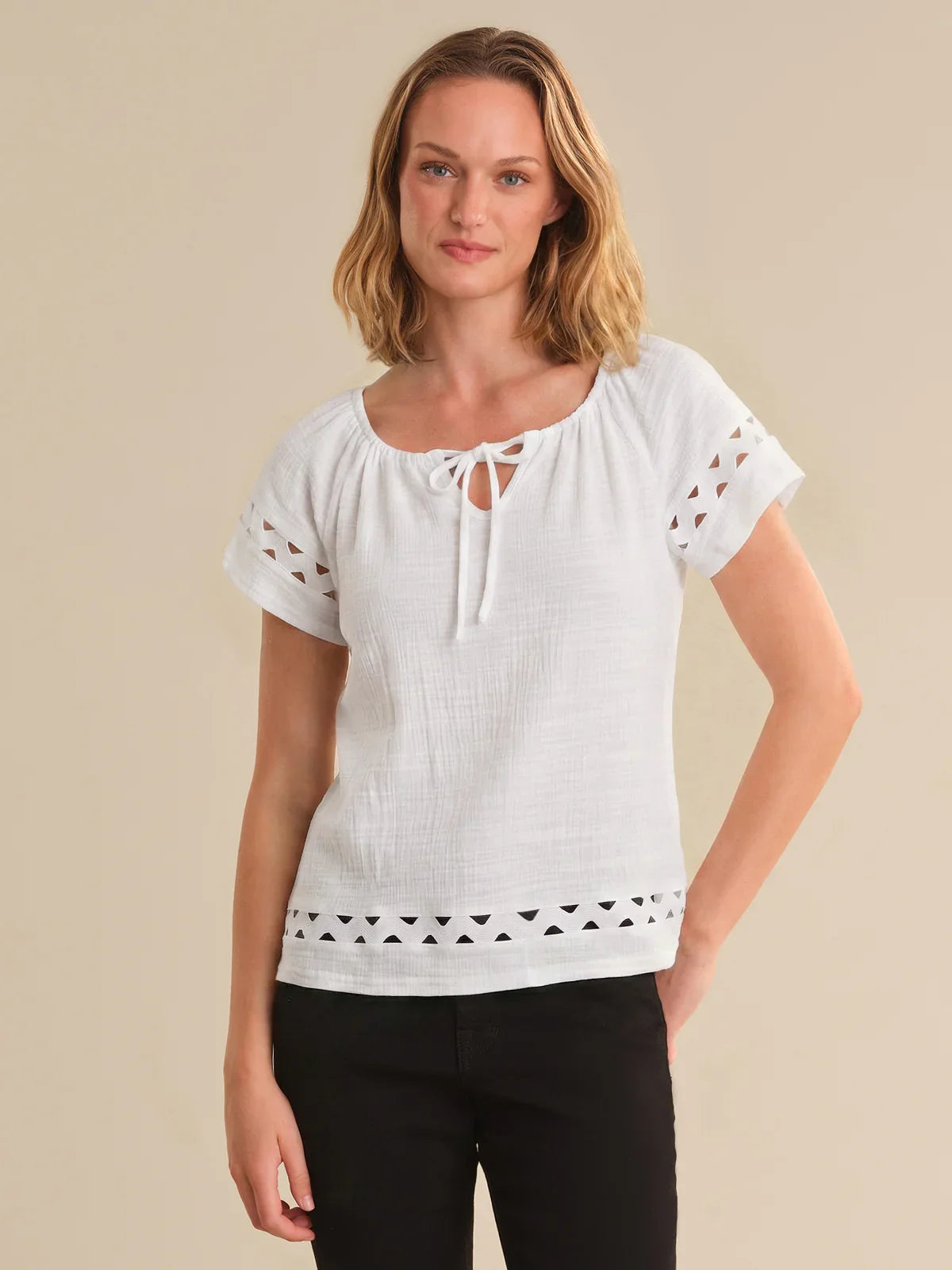 Woman wearing a white blouse with lace details on a beige background