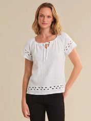 Woman wearing a white blouse with lace details on a beige background