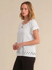 Woman wearing a white blouse with lace details on a beige background