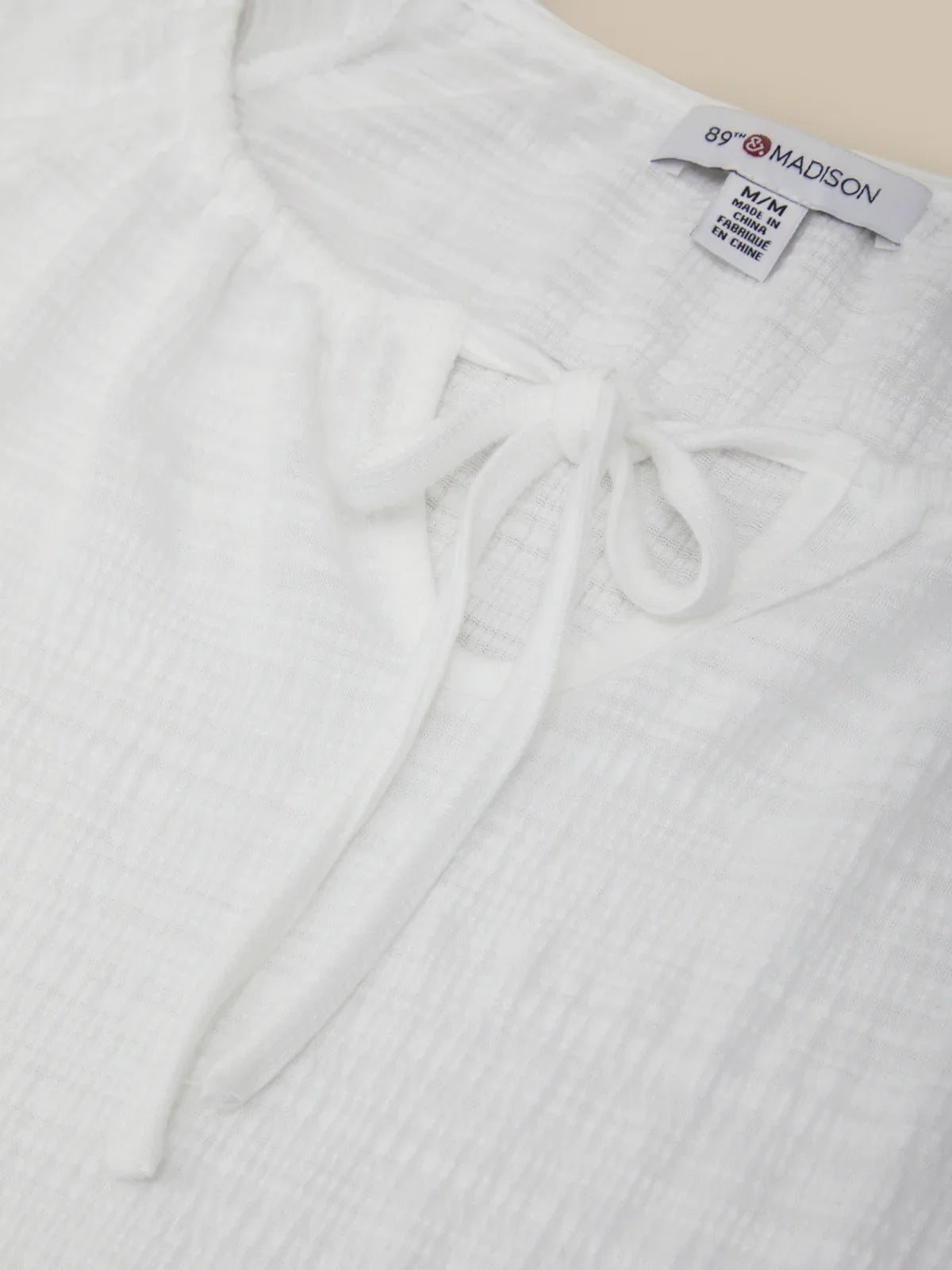 White textured garment with a brand label on a light background