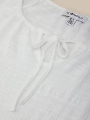 White textured garment with a brand label on a light background