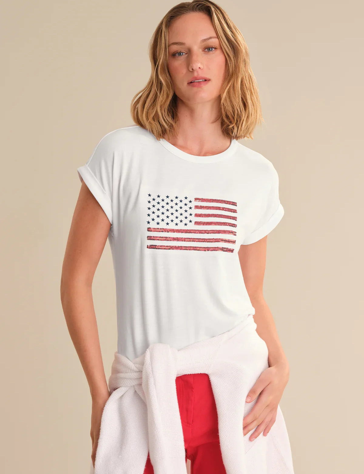 Woman wearing a white t-shirt with an American flag design on a beige background