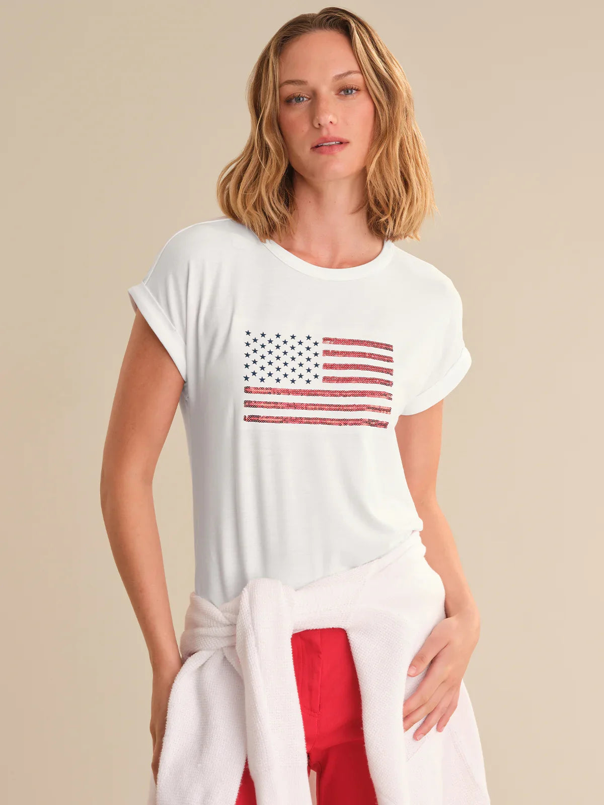 Woman wearing a white t-shirt with an American flag design on a beige background