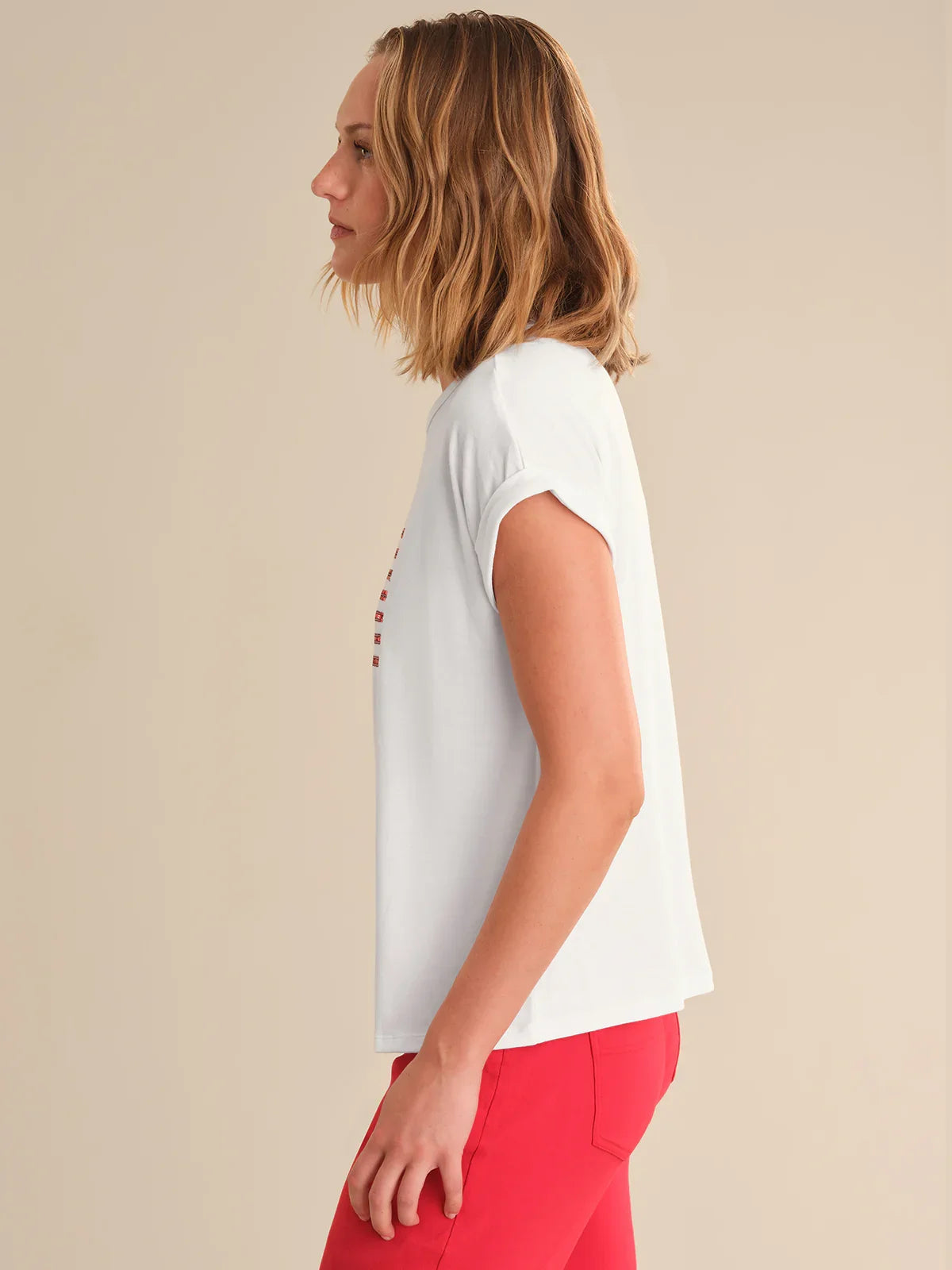 Woman wearing a white t-shirt with red accents on a beige background