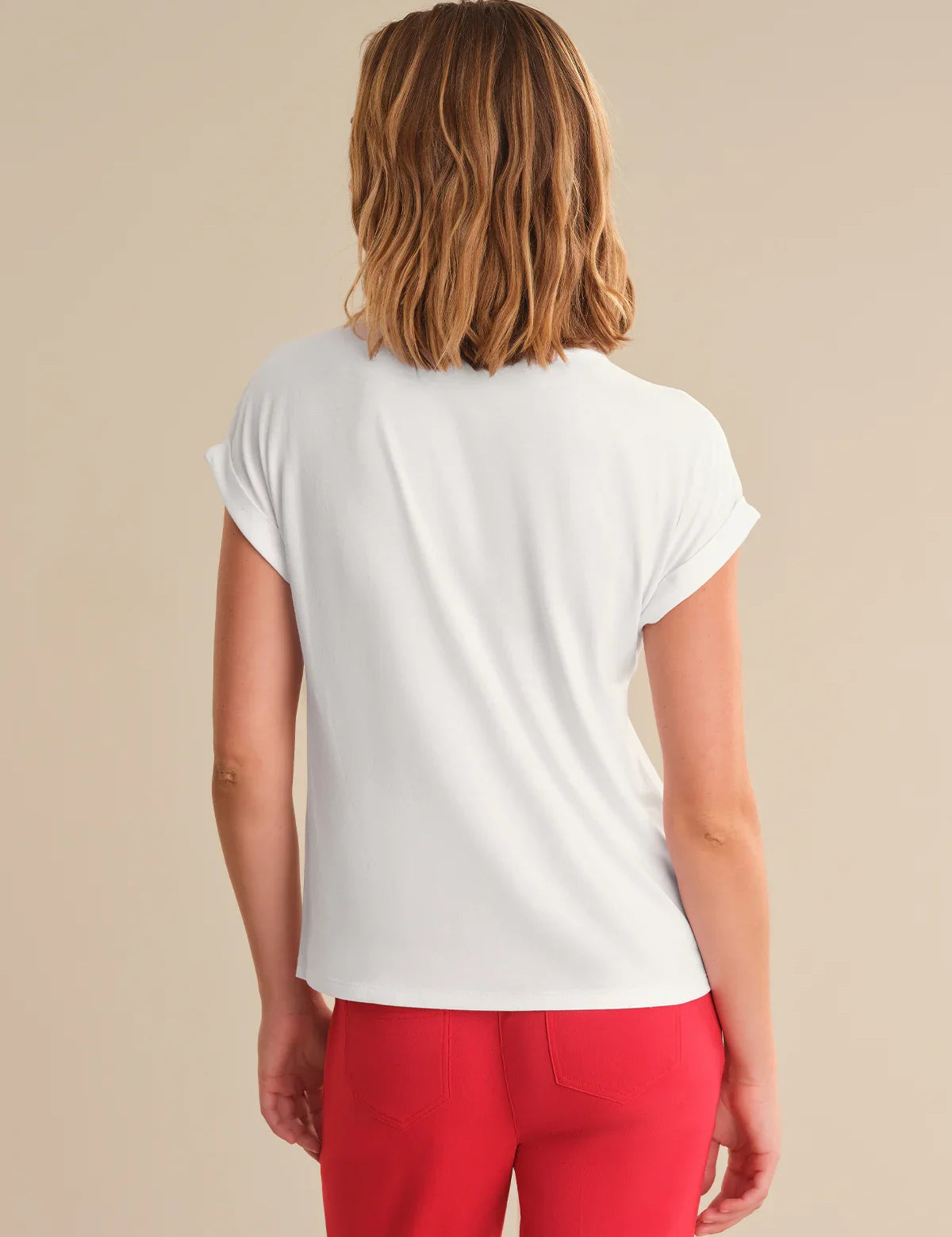 Person wearing a white t-shirt and red pants on a beige background