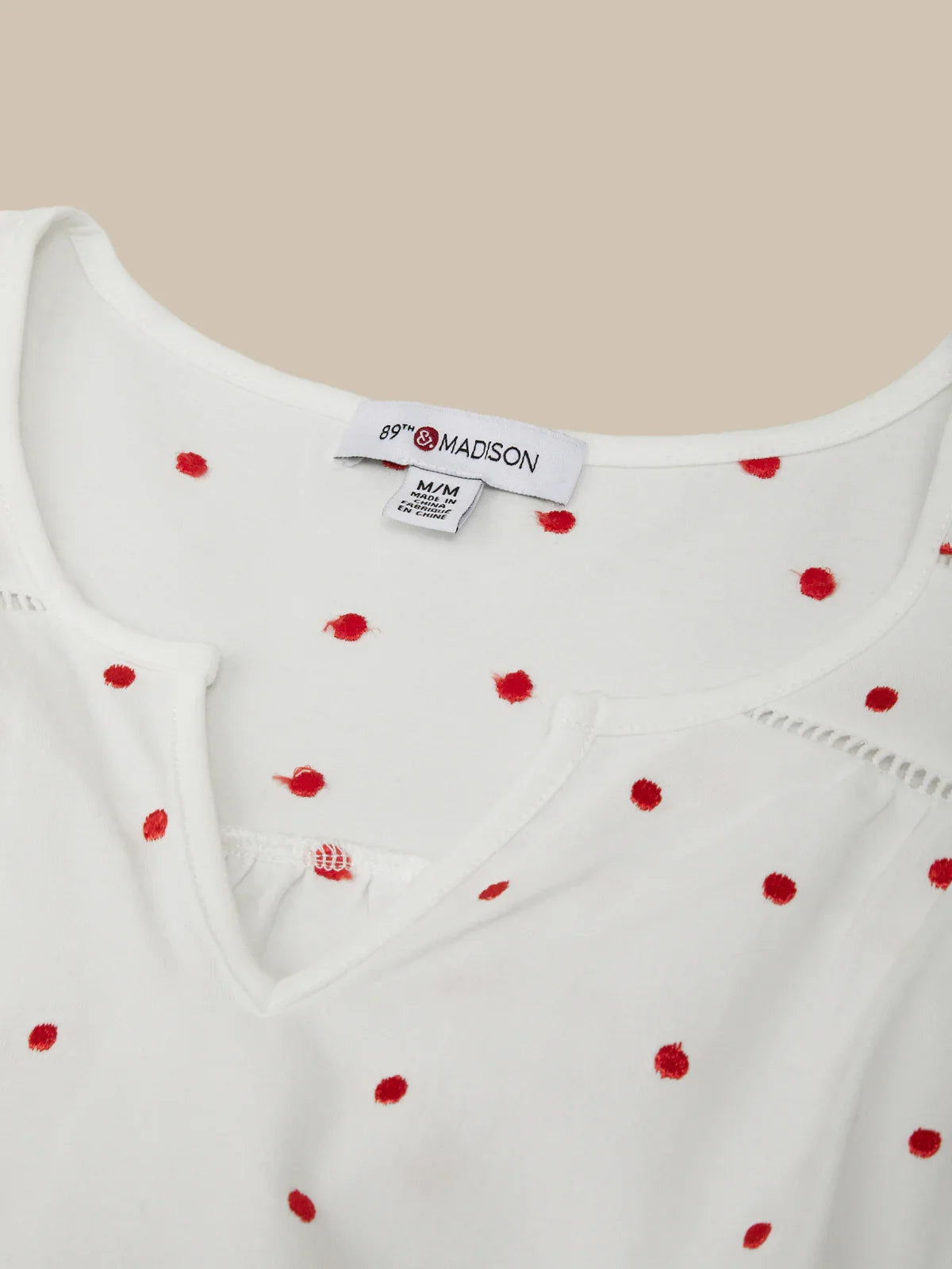 White top with red polka dots and 'Madison' brand label on a beige background
