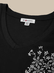 Black t-shirt with white floral embroidery and 'Madison' label on a beige background