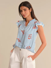 Woman wearing a blue and white striped top with red floral patterns on a beige background