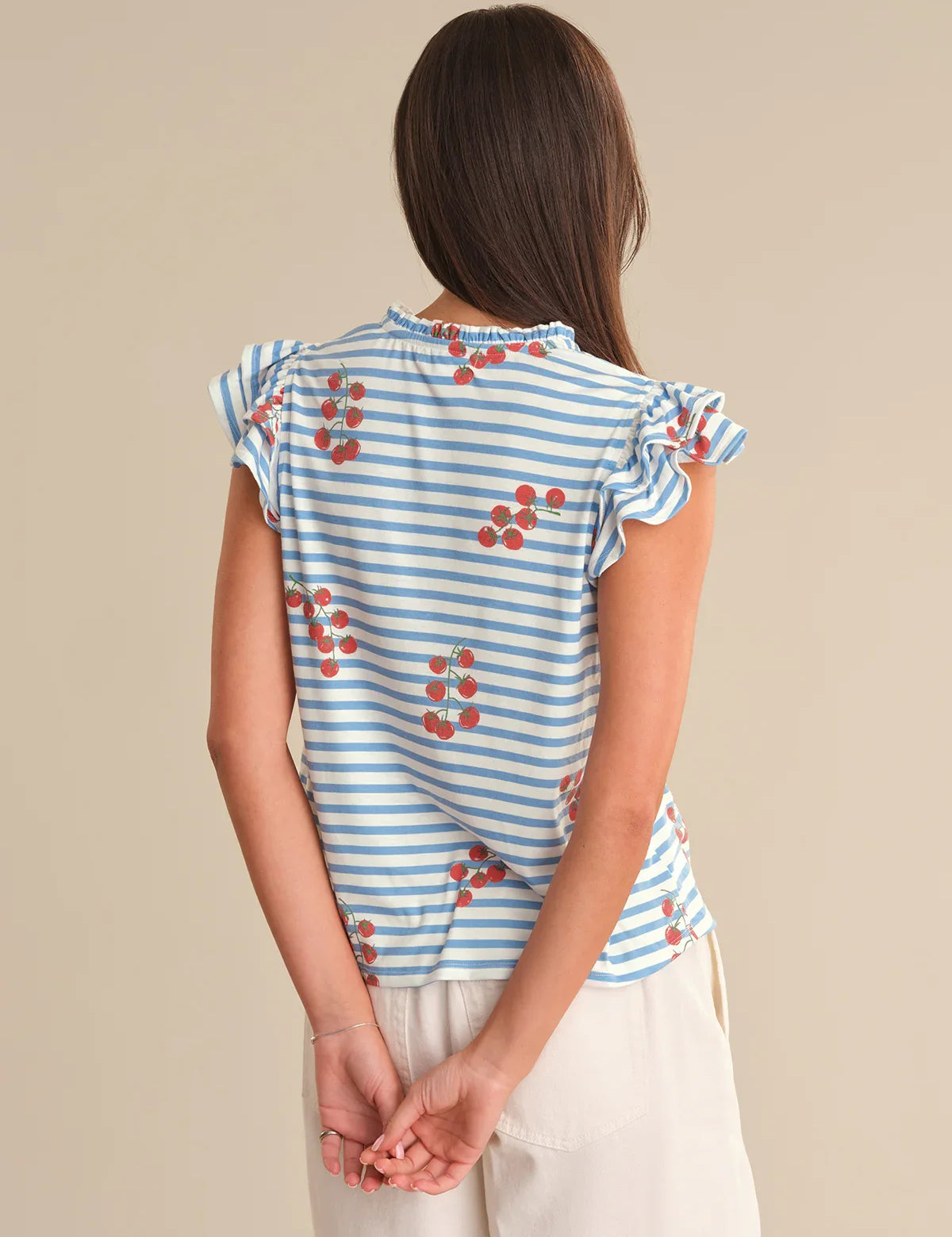 Woman wearing a blue and white striped top with red floral patterns on a beige background