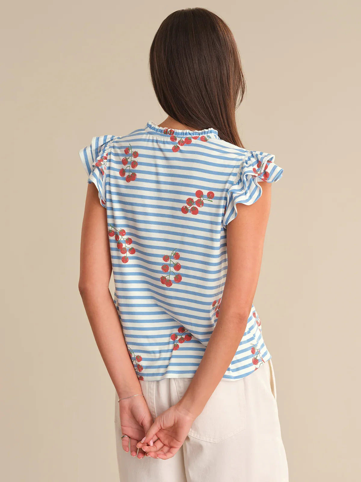 Woman wearing a blue and white striped top with red floral patterns on a beige background