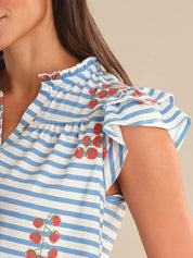 Woman wearing a blue and white striped top with tomato designs on a neutral background