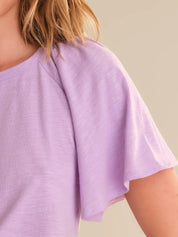 Close-up of a person wearing a light purple top against a neutral background