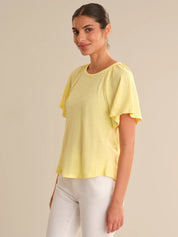 Woman wearing a yellow top with ruffled sleeves on a beige background