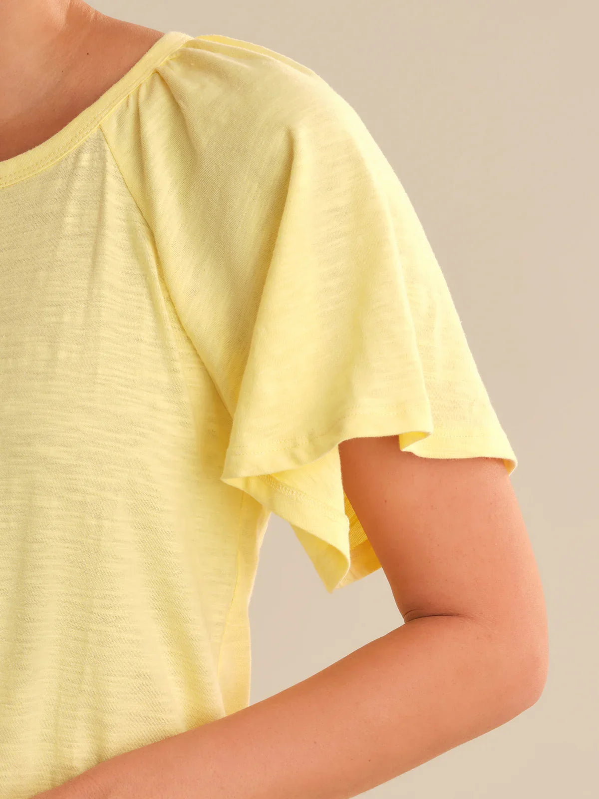 Yellow top worn by a person on a plain background
