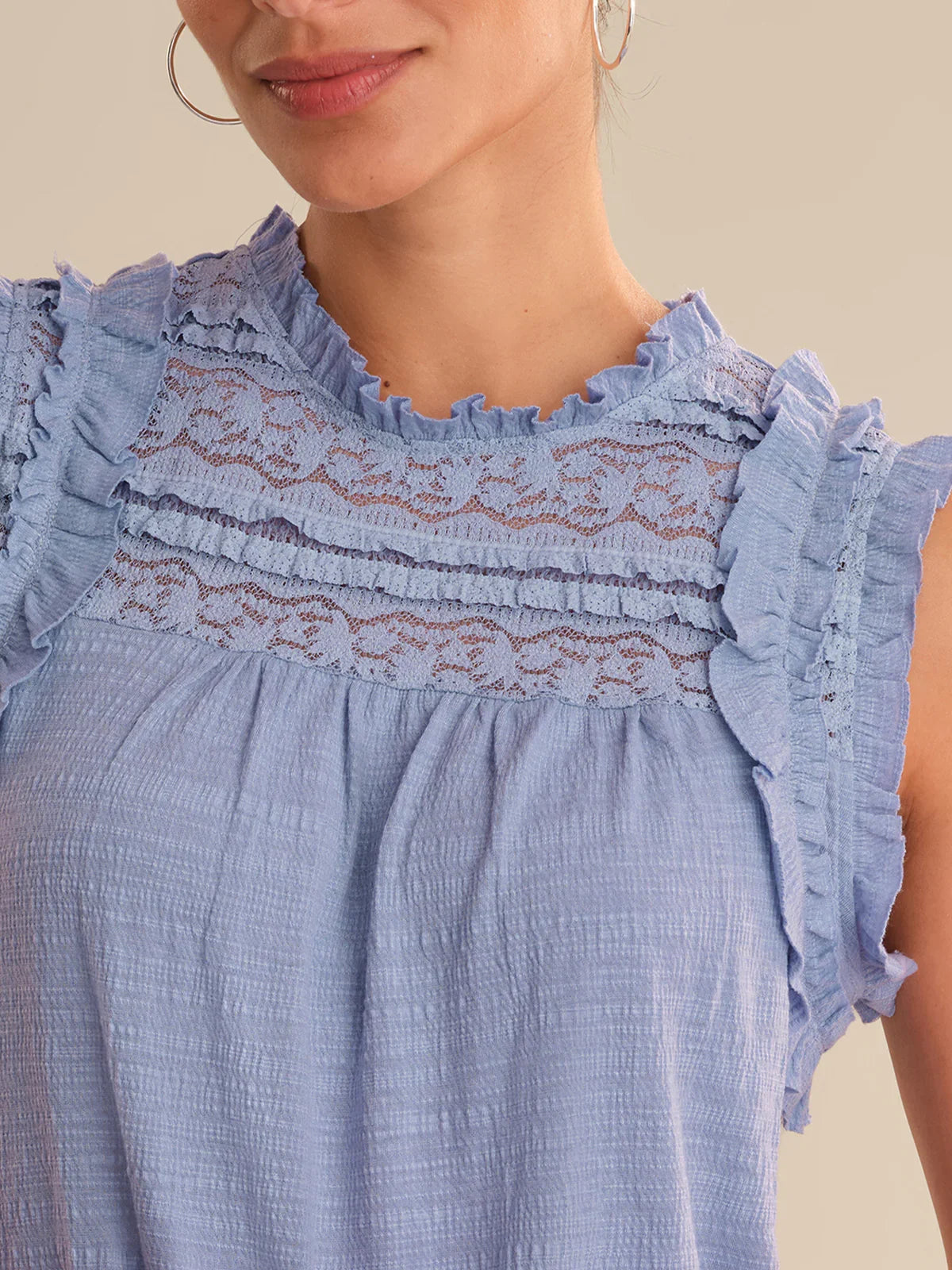Close-up of a blue dress with lace detailing on a neutral background
