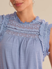 Close-up of a blue dress with lace detailing on a neutral background