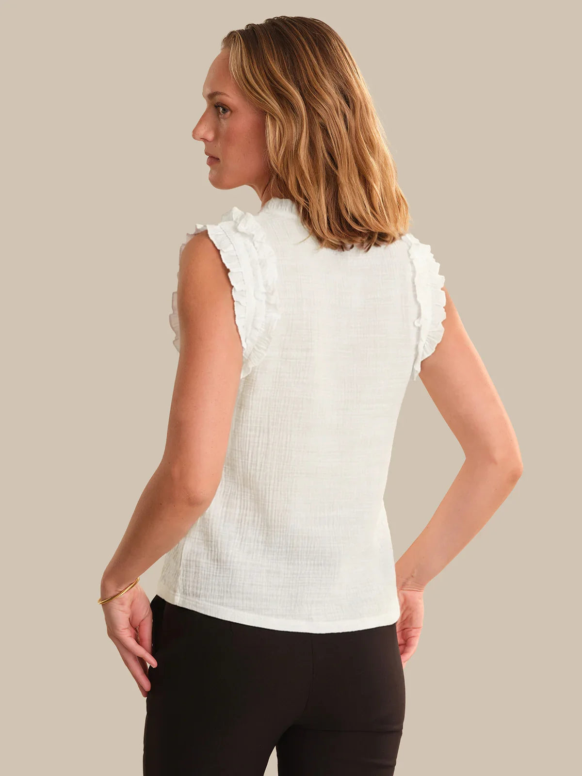 Woman wearing a white blouse with ruffled sleeves on a beige background