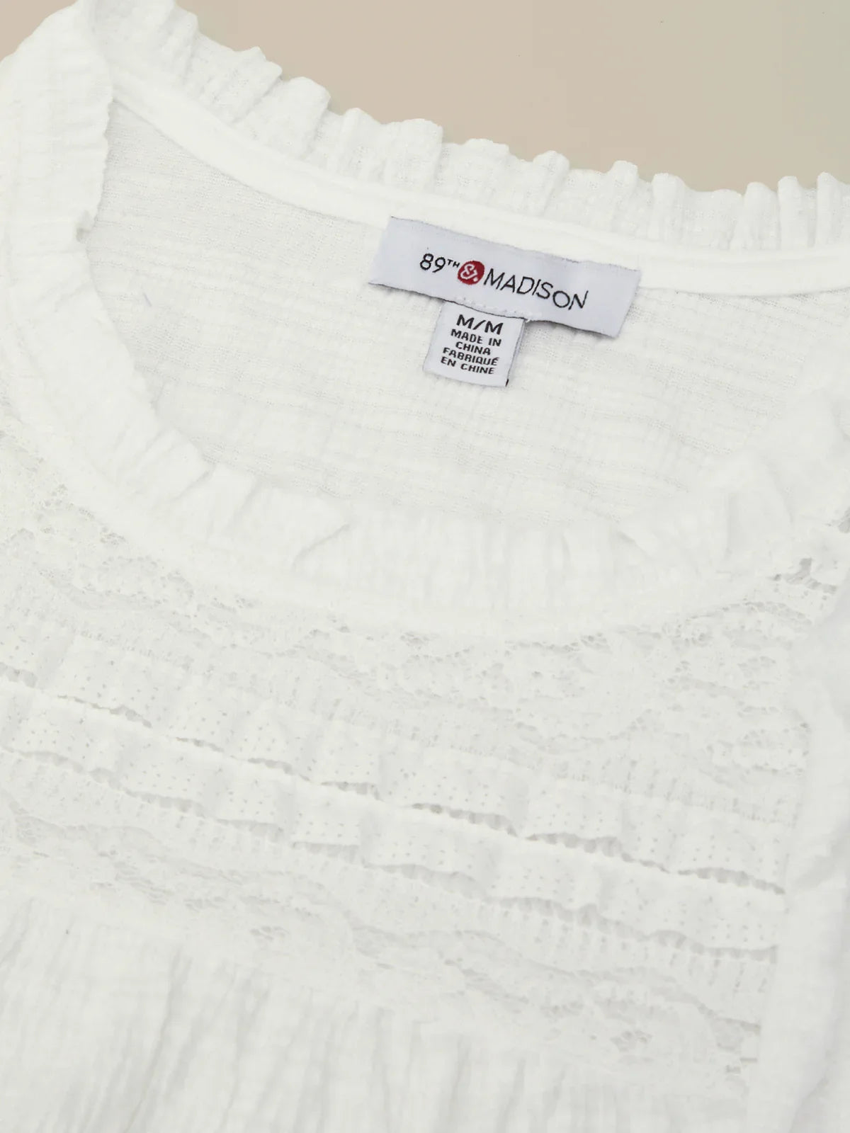 Close-up of a white textured fabric with a brand label on a beige background
