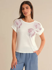 Woman wearing a white t-shirt with floral patterns on a beige background