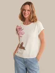 Woman wearing a white t-shirt with a floral design on a beige background